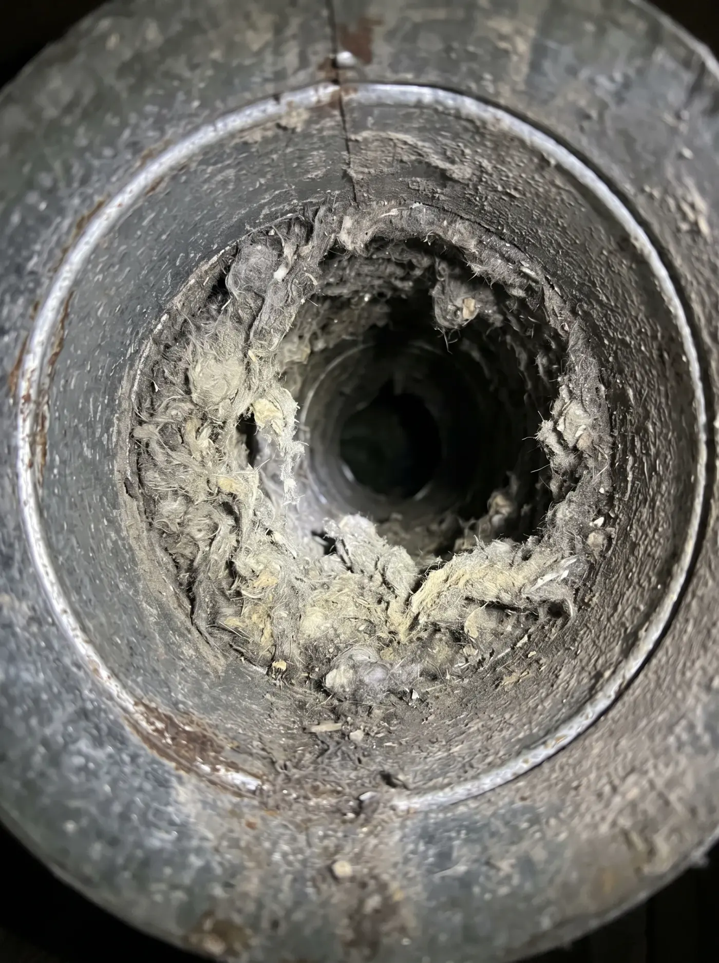 Dryer duct, lint packed inside beside the cleared metal before cleaning