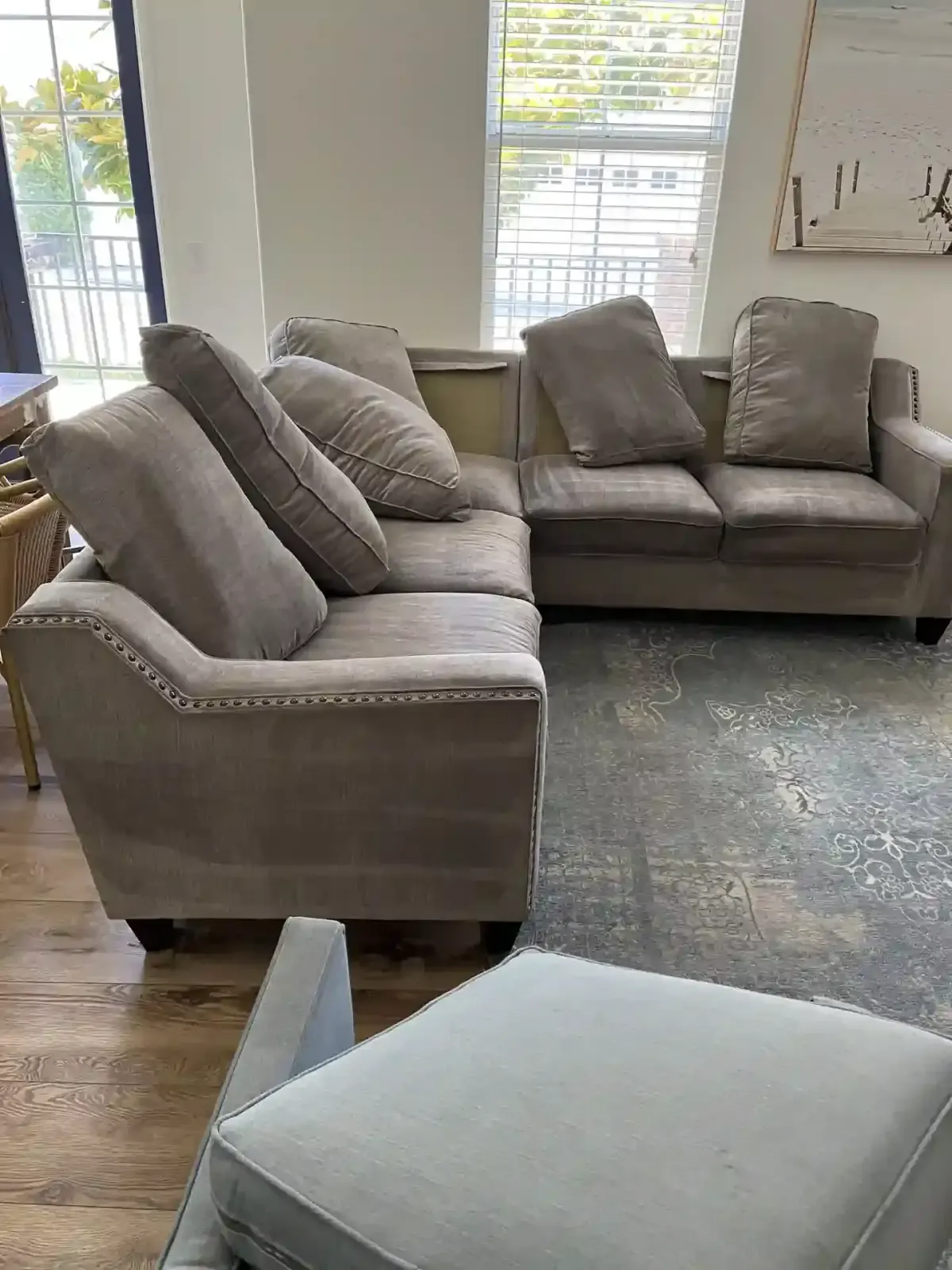 A sectional sofa and ottoman in a living room with a rug and hardwood floors.