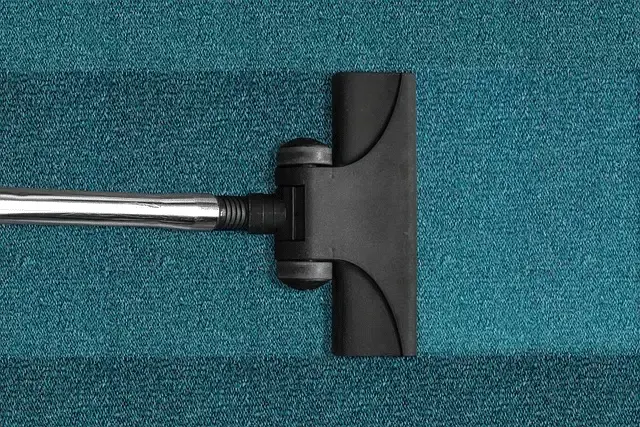 Vacuum cleaner head cleaning a teal carpet.