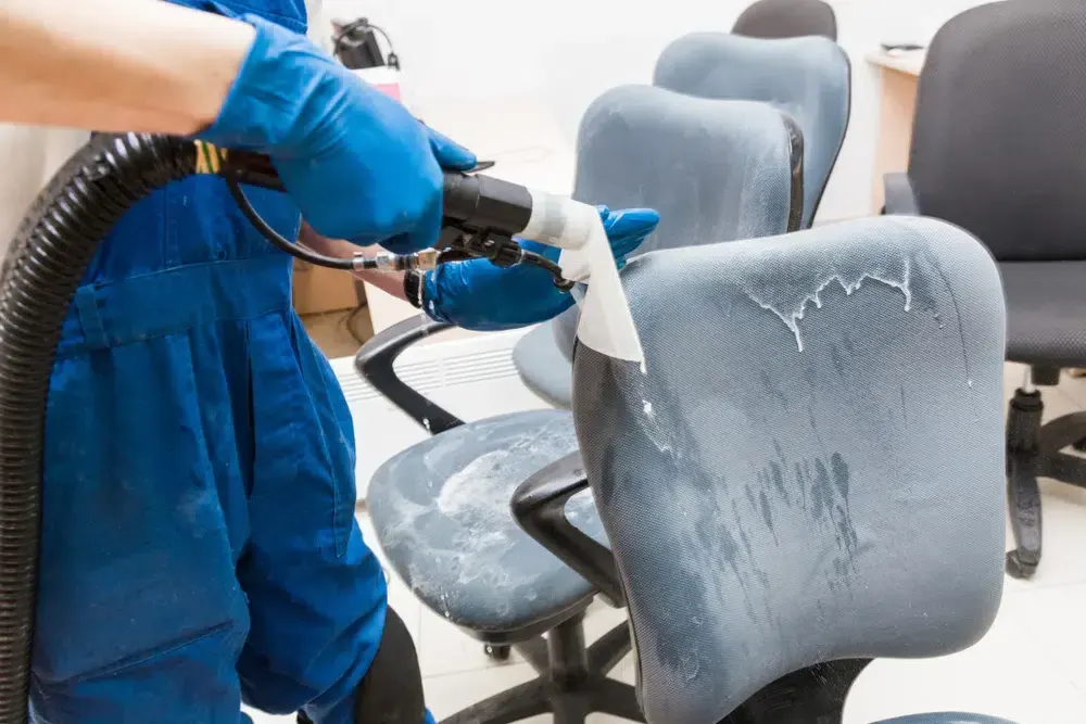 Professional cleaning of office chairs with a specialized upholstery cleaning machine.