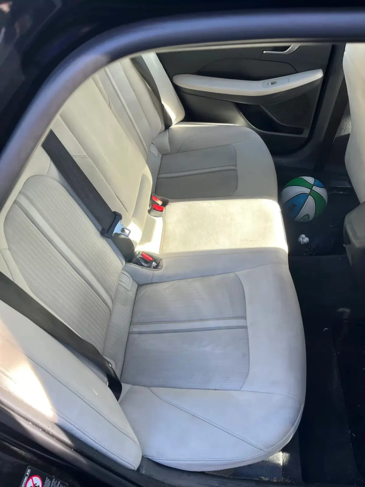 Cleaned car interior with light-colored seats and a basketball on the floor.