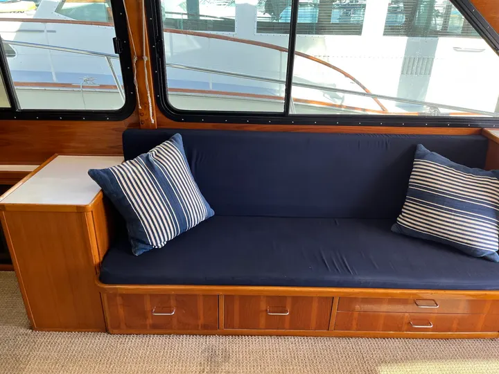 Navy settee inside a boat cabin, with the hull visible through the windows