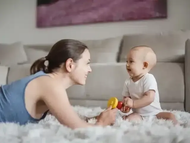 Mother and baby playing on a fluffy carpet in a living room