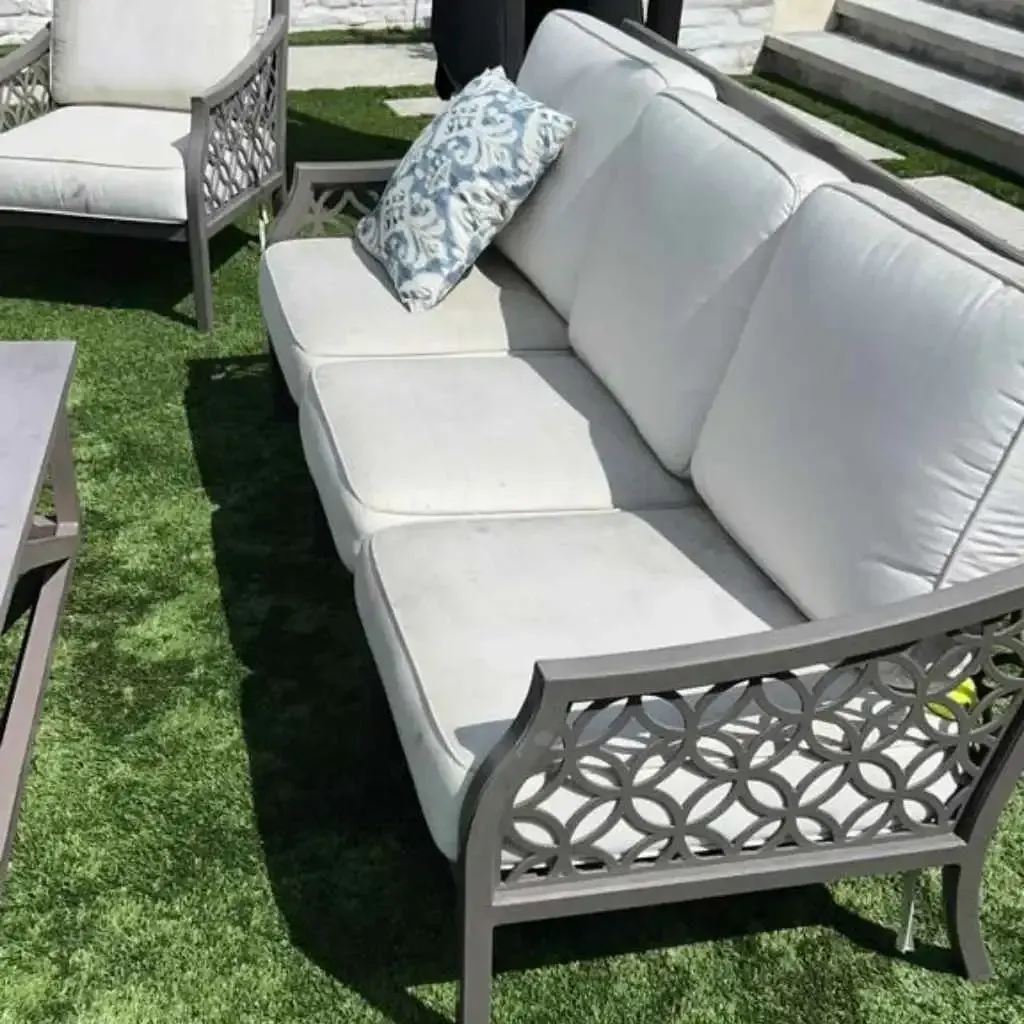 Outdoor sofa and chair with white cushions on artificial grass