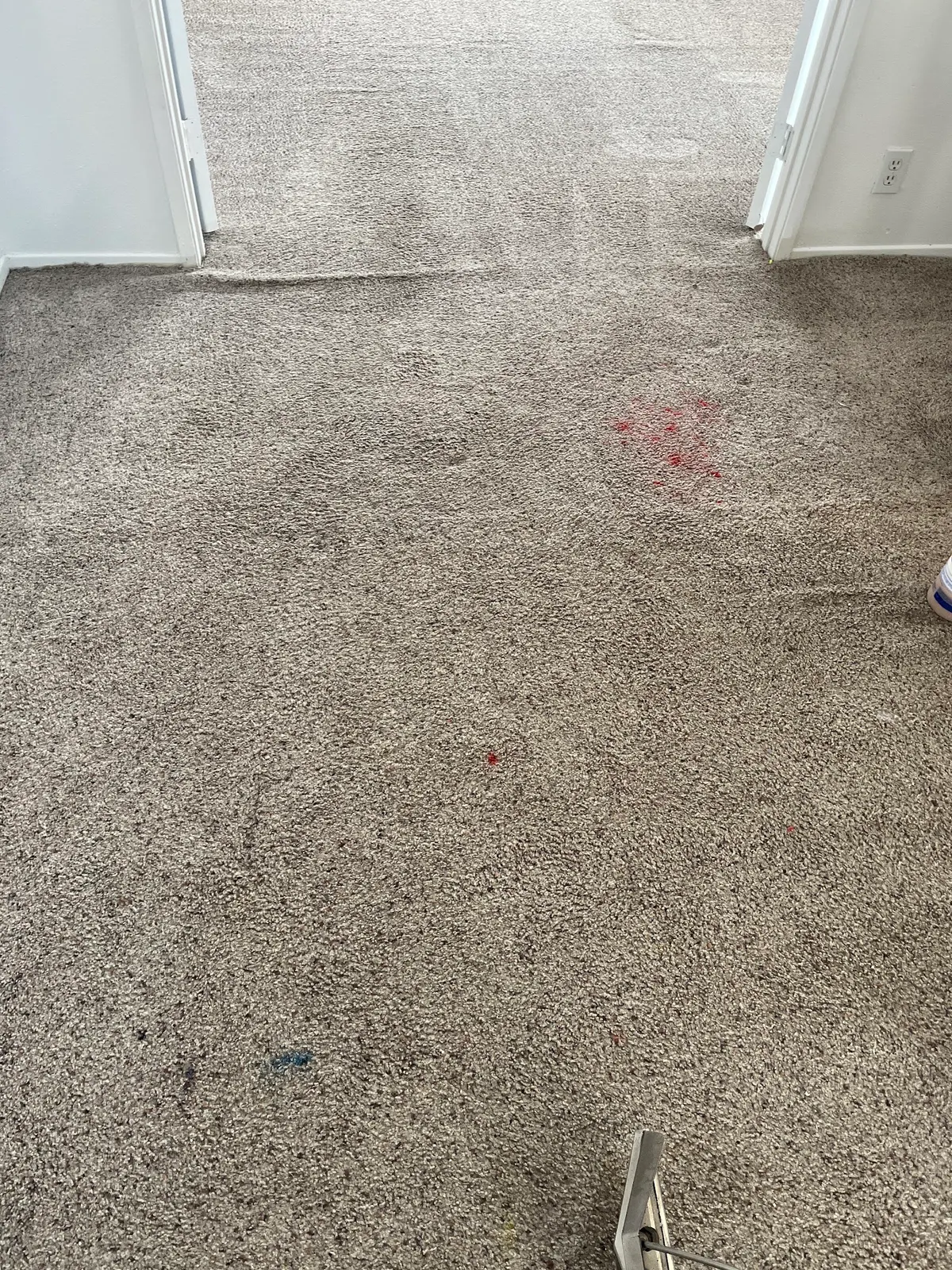 Red stain on a bedroom carpet with the cleaning wand at the edge