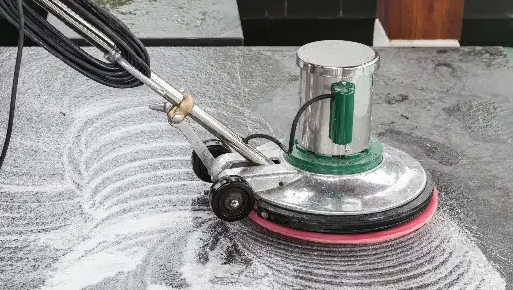 Floor buffer machine cleaning a hard surface floor with soap suds.